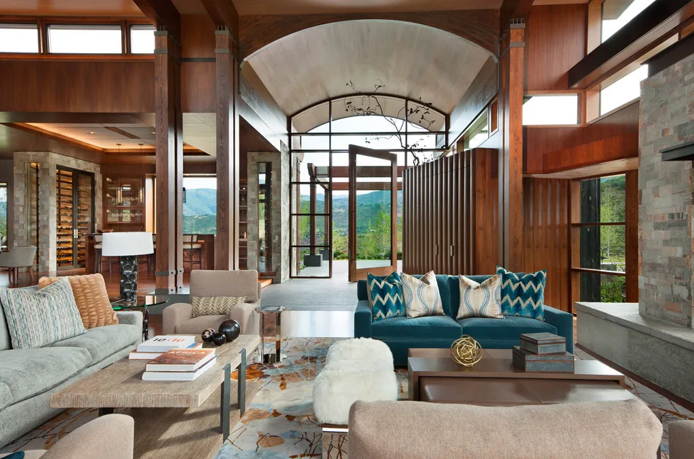 Living room at Elk Peak Ranch by Charles Cunniffe Architects emphasizes wood detailing and large curved ceiling.