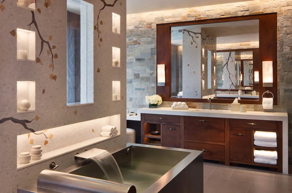 Elk Peak Ranch bathroom features a metal tub, illuminated decorative wall niches, and a wood vanity with dual sconces beside a large mirror.
