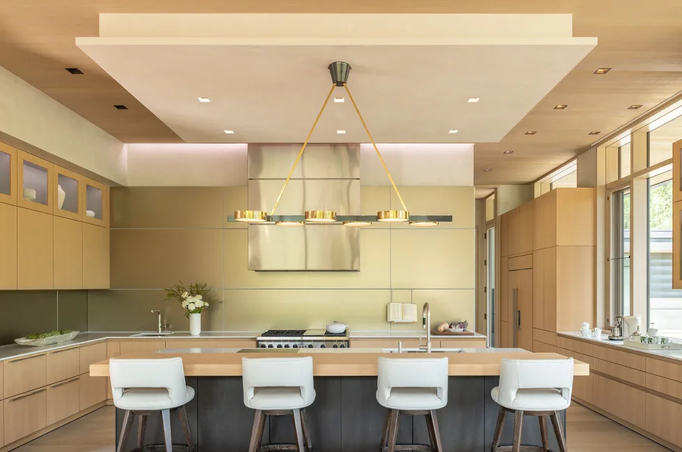 Kitchen interior with wood cabinetry, large island seating, and built-in appliances.