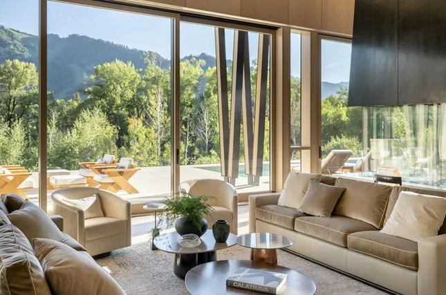 Living room with floor-to-ceiling glazing framing an exterior patio and mountain landscape.