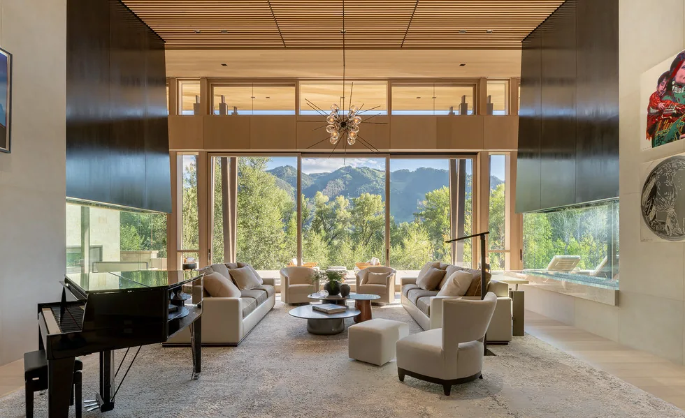 Living room with large windows framing mountain views and modern furnishings.