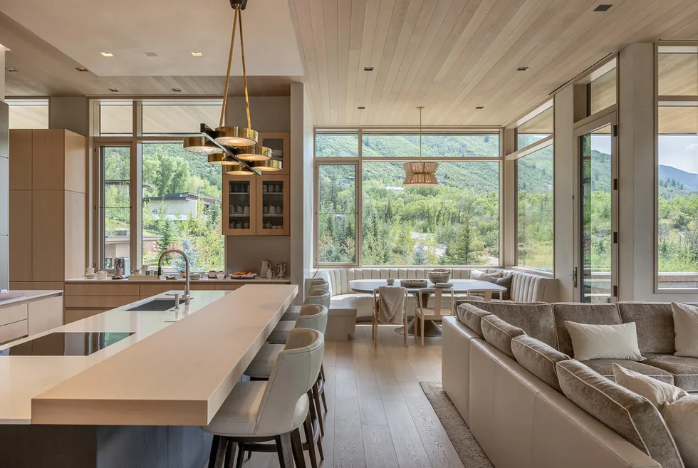 Open kitchen and dining area with floor-to-ceiling corner windows and wood ceiling and flooring.