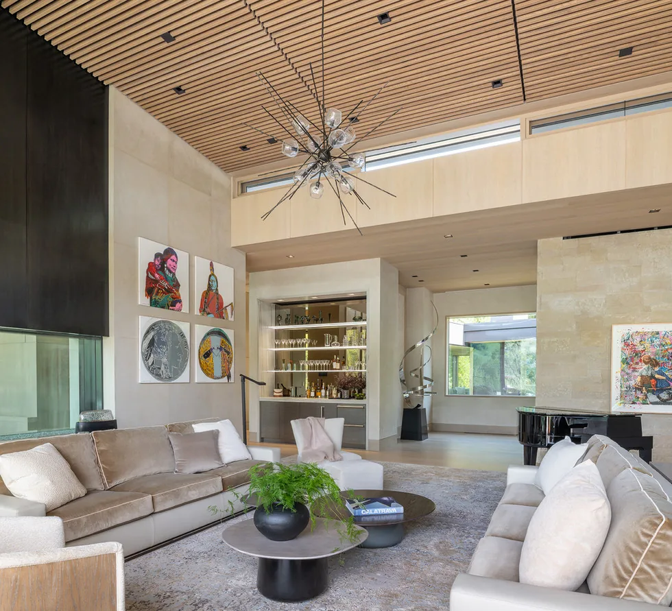 Living room interior with vaulted wood slatted ceiling, recessed lighting, and a built-in bar area.