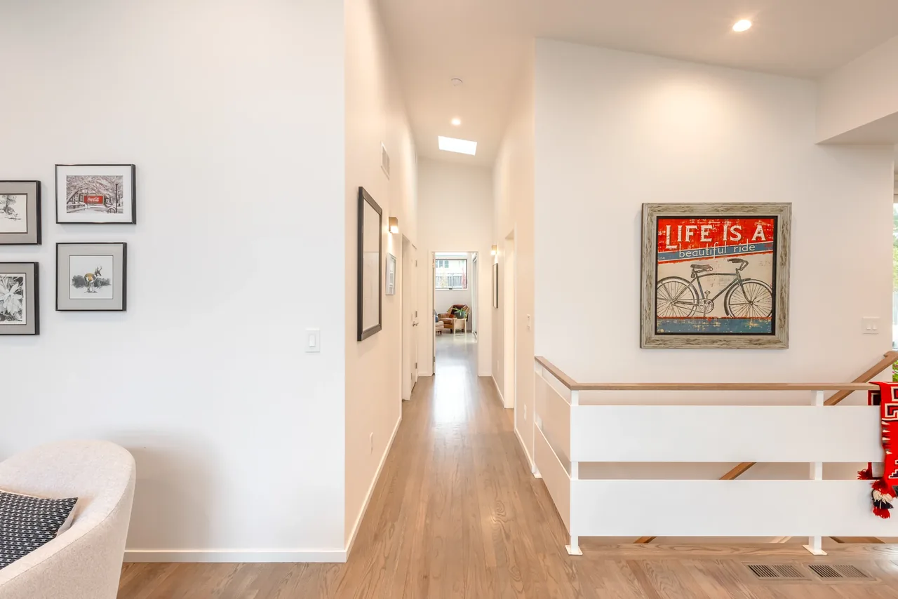 Hallway in Centennial Modern Ranch with light wood flooring and framed bicycle artwork.