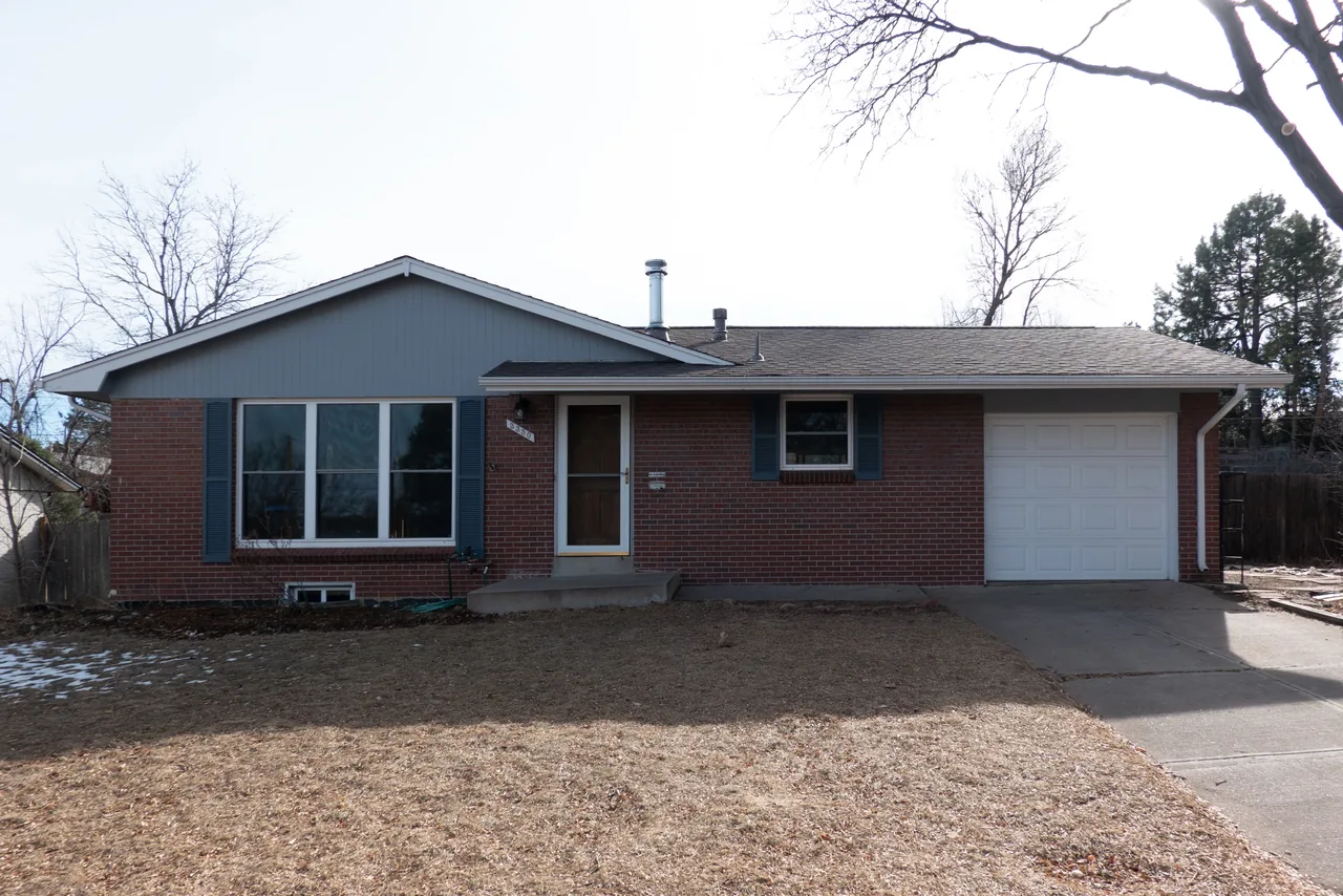 The Centennial Modern Ranch features a brick facade with a gable roof and attached garage.
