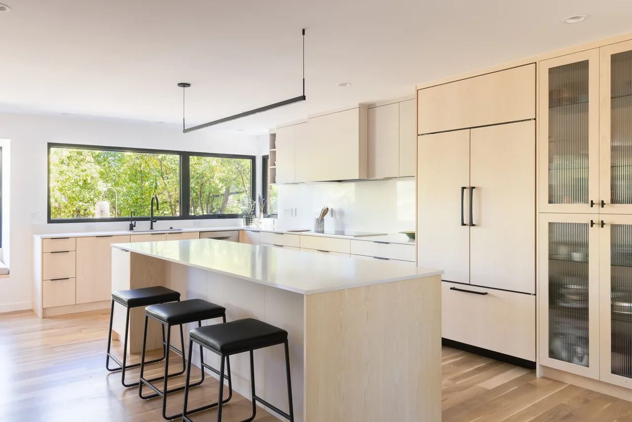 Kitchen interior with an island and floor-to-ceiling storage cabinets featuring frosted glass doors.