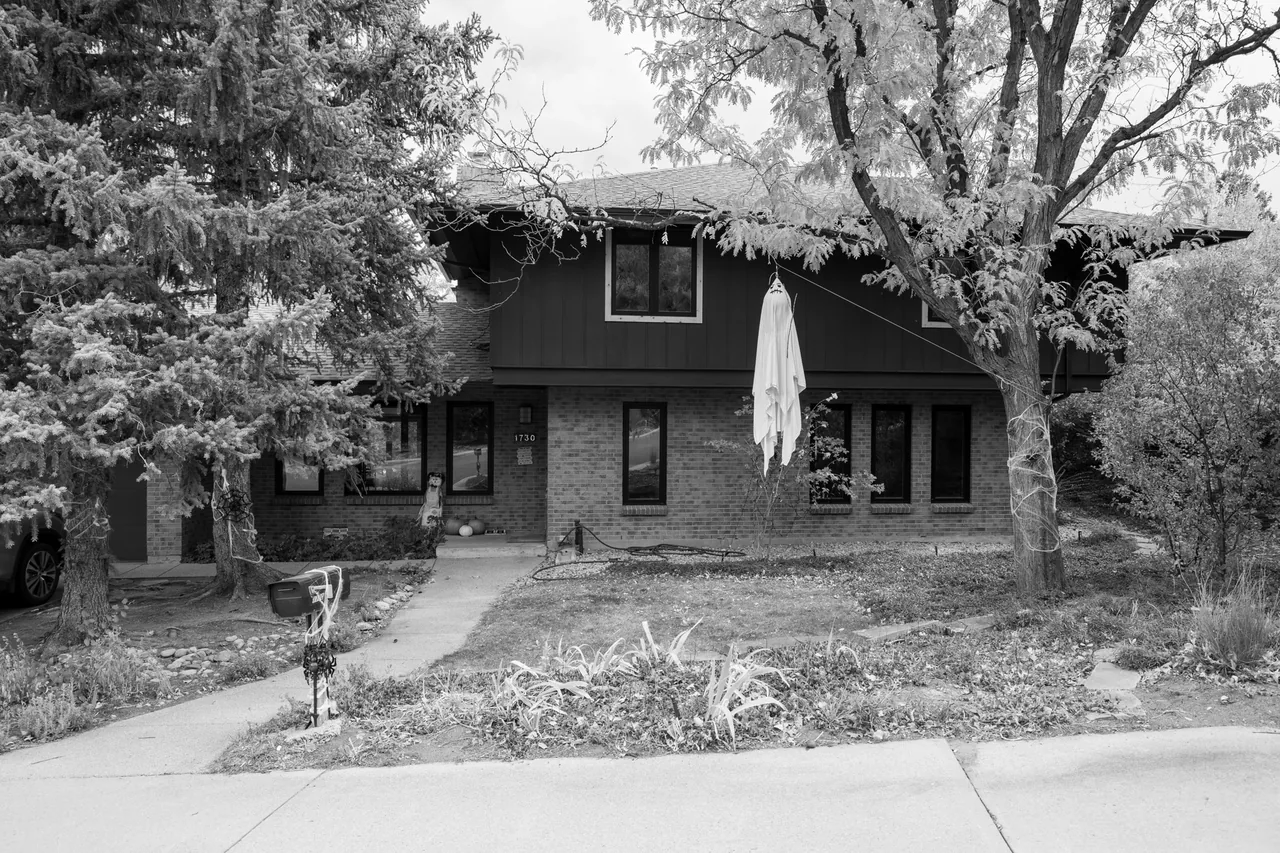 Exterior front view of a two-story brick house with symmetrical window placement and surrounding vegetation.