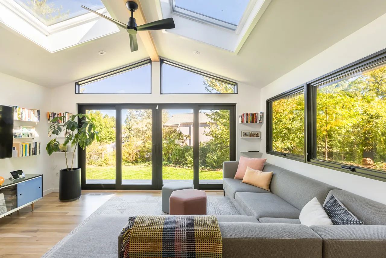 Living room with vaulted ceiling, clerestory windows, skylights, and large sliding glass doors opening to the exterior.