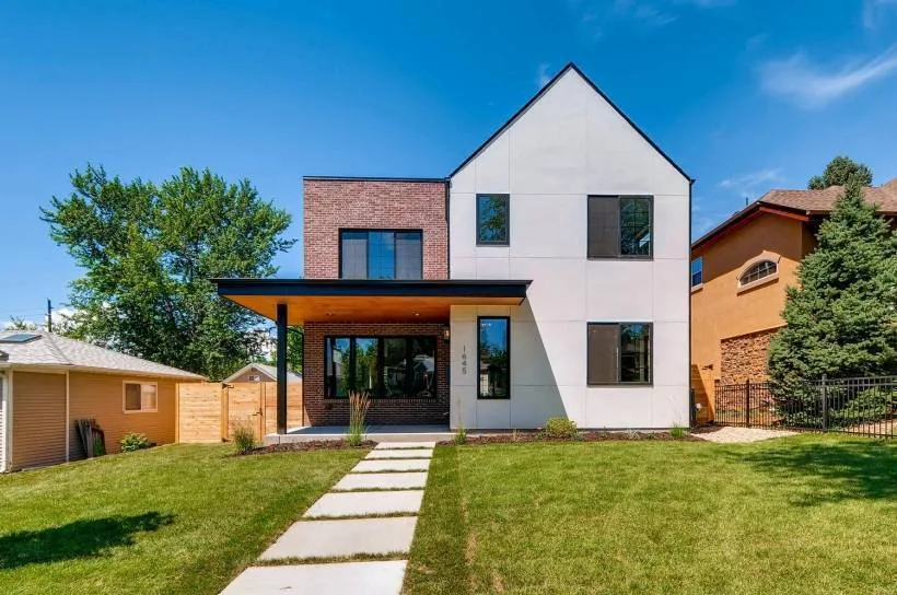 Front exterior view of a modern house featuring brick and stucco walls, pitched roof, and covered patio with wood ceiling.