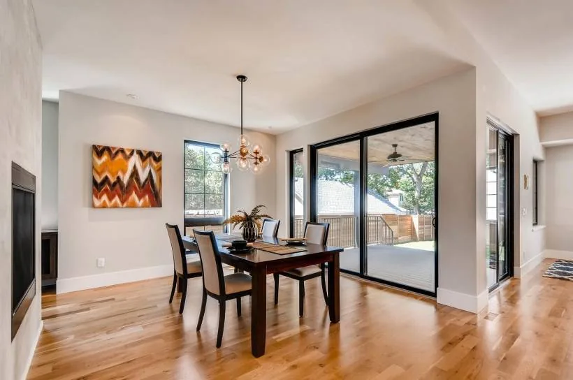 Dining room with wood dining table and chairs, recessed lighting, and sliding glass doors opening to an outdoor covered patio.