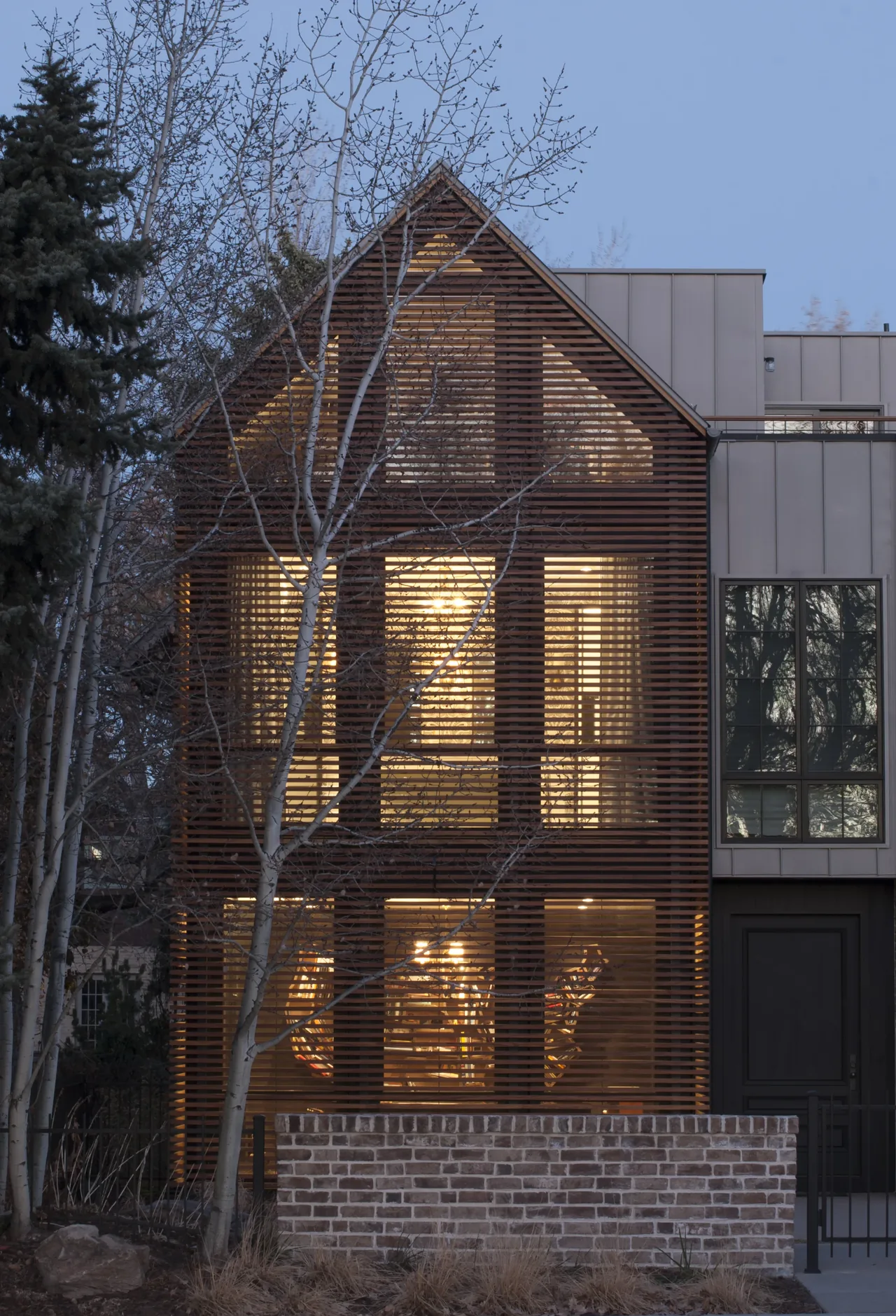 Denver Residence 1 features a slatted wood facade with large windows and a brick wall at the front.