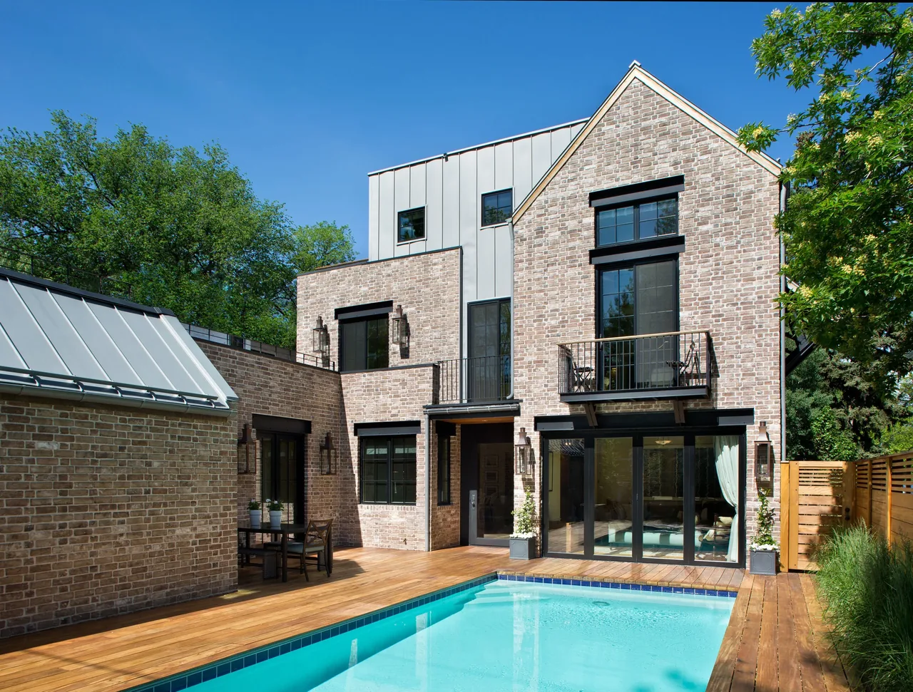 Exterior rear of Denver Residence 1 shows brick facade with balconies over a wood deck and a rectangular pool.