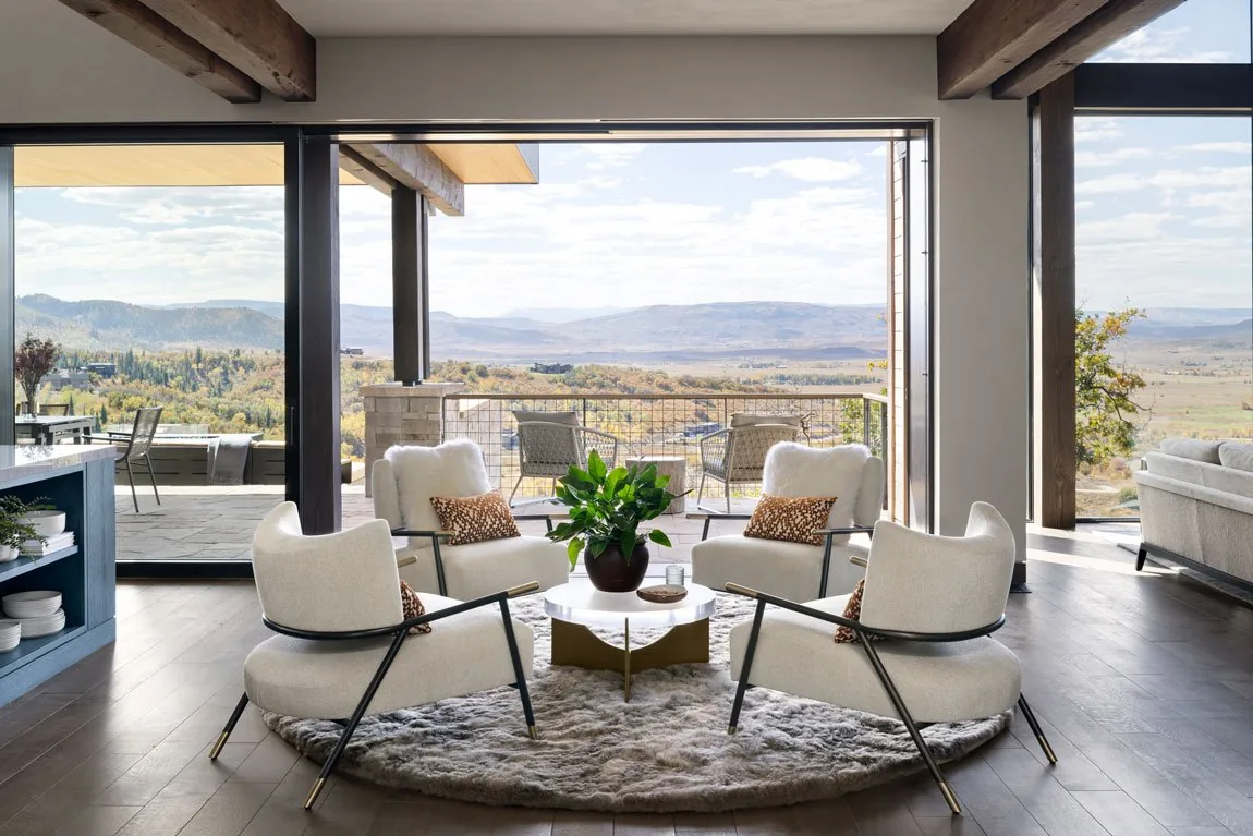 Living area with floor-to-ceiling glazing opening to a patio and mountain views.