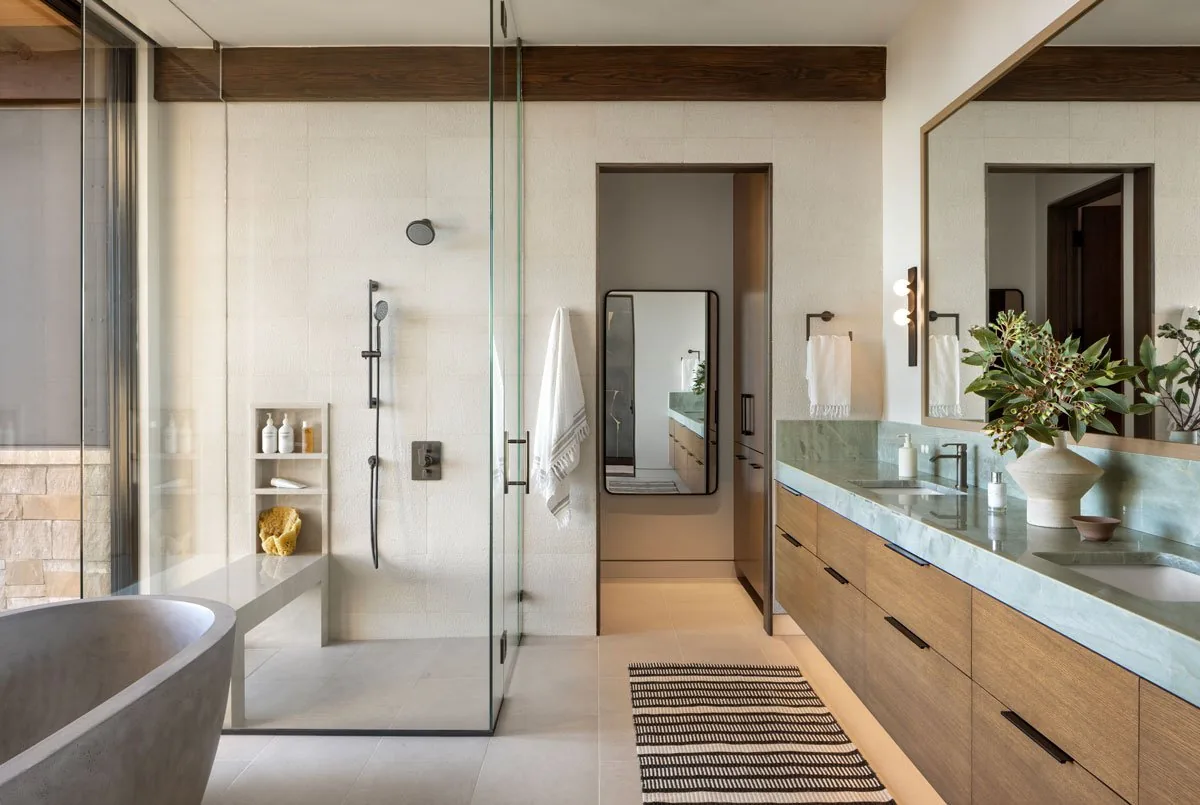Bathroom featuring glass shower enclosure, wooden floating vanity with double sinks, and freestanding tub.