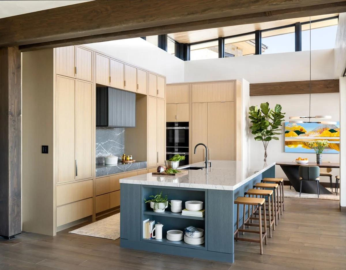 Kitchen featuring a large island with marble countertop, light wood cabinetry, and clerestory windows.