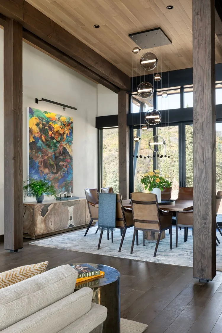 Dining room with wood ceiling and beams, floor-to-ceiling glazing, and hanging globe pendant lights.