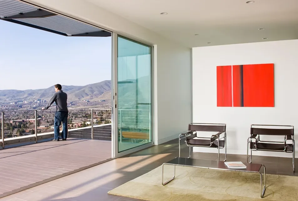 Living room with sliding glass door opening onto a balcony overlooking a hilly landscape.