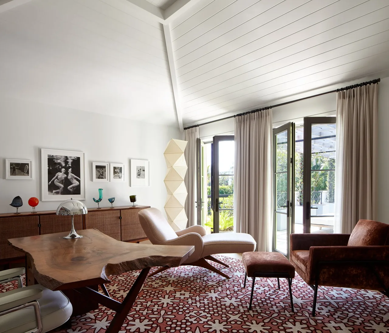 Living room with vaulted ceiling featuring large glass doors opening to the exterior and custom wood furniture.