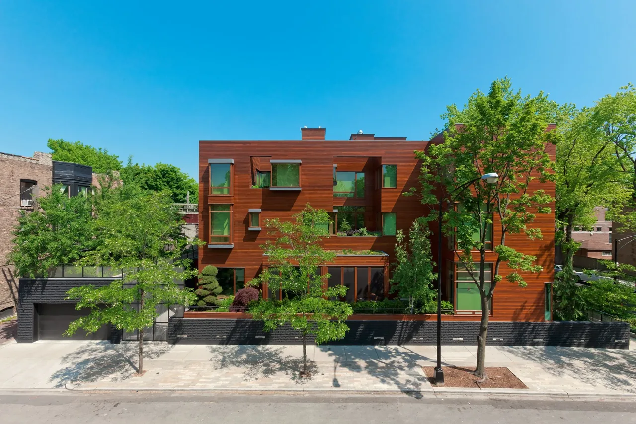 Exterior front view of a modern three-story residence clad in horizontal wood siding with varied rectangular windows and landscaping.