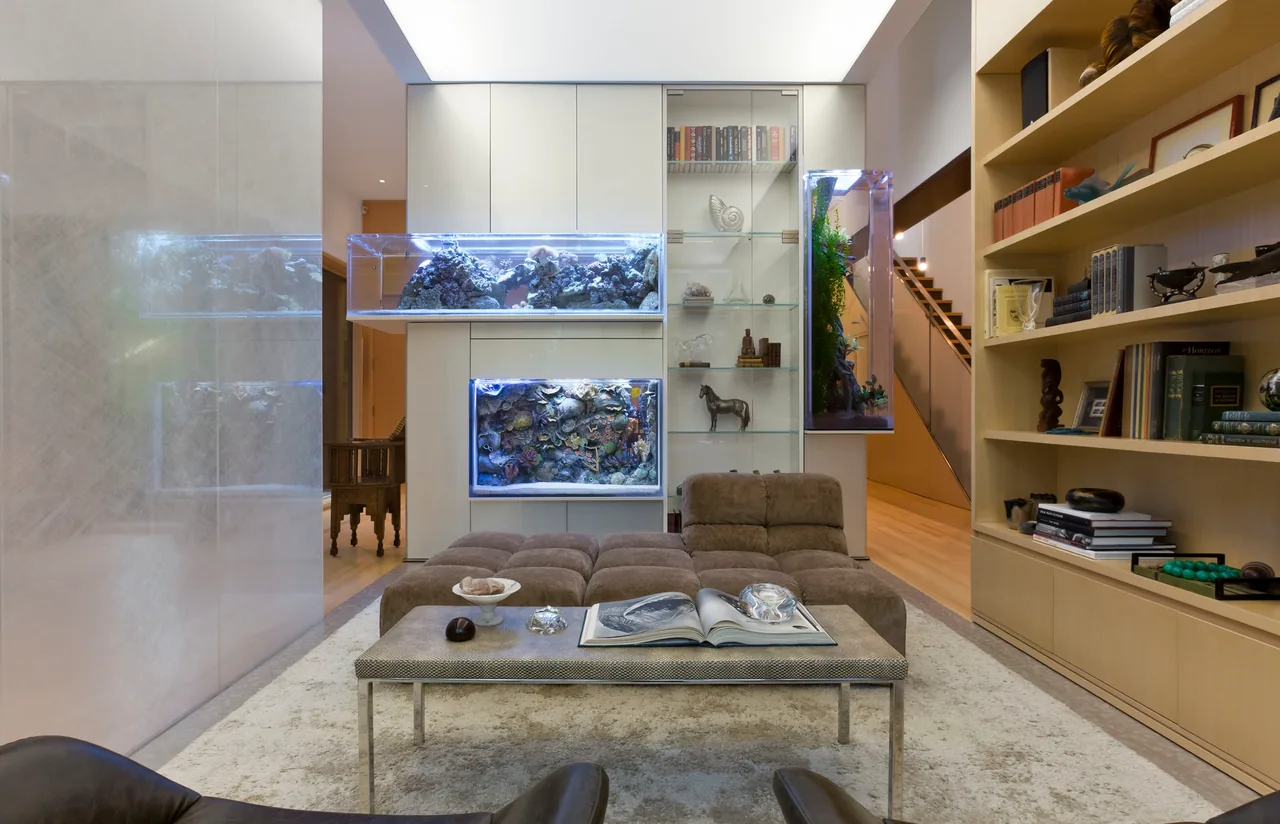Living room with built-in aquariums and shelving, a sectional sofa, and a staircase in the background.