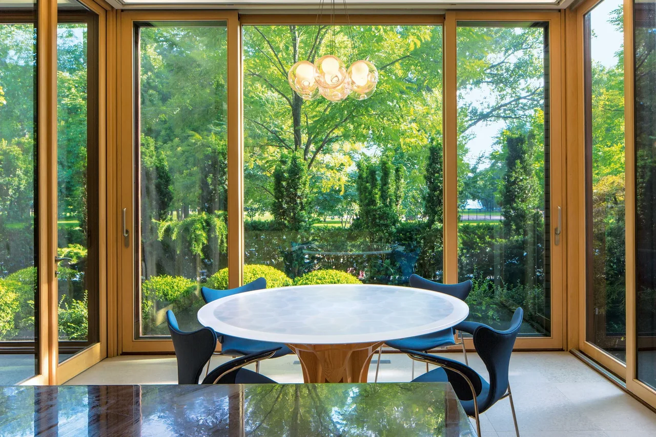 Dining area with floor-to-ceiling glass windows overlooking a landscaped garden.