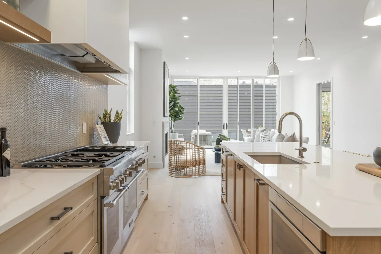Modern kitchen featuring a white island countertop, built-in gas range, woven bar stool, and sliding glass doors to the patio.