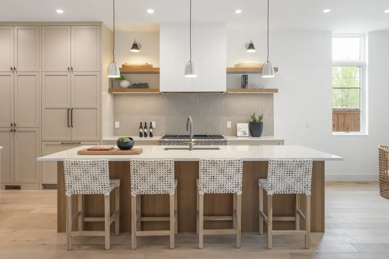 Kitchen with a white island countertop, wooden cabinetry, and three pendant lights above the island.