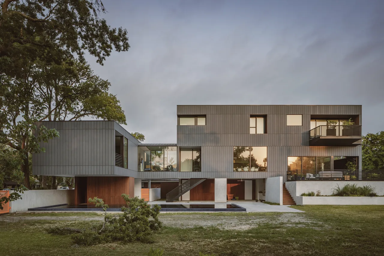 The Grennoch Residence by CONTENT Architecture features gray vertical wood siding and a rectangular pool as part of its modern design.