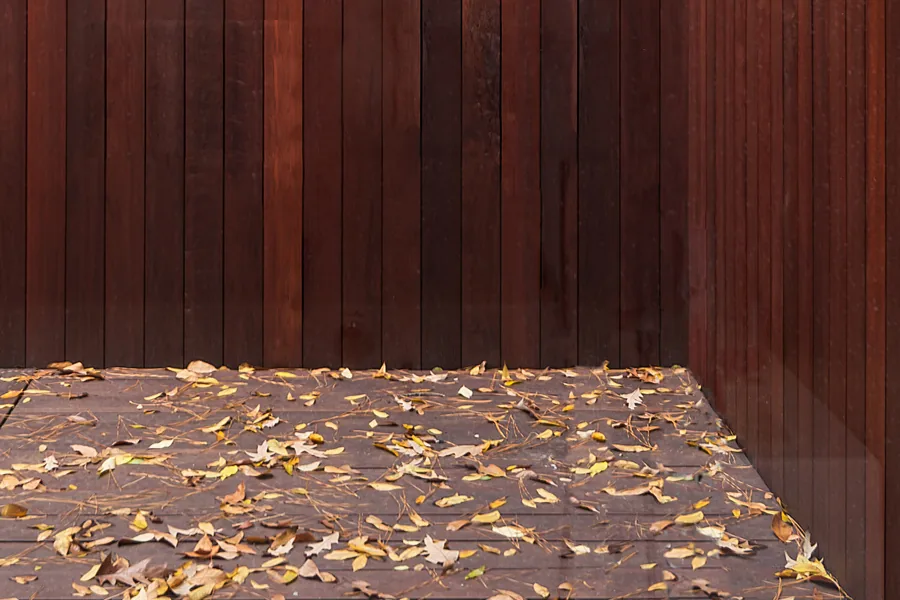 Exterior corner of the Grennoch Residence features vertical redwood siding and a leaf-strewn outdoor surface.