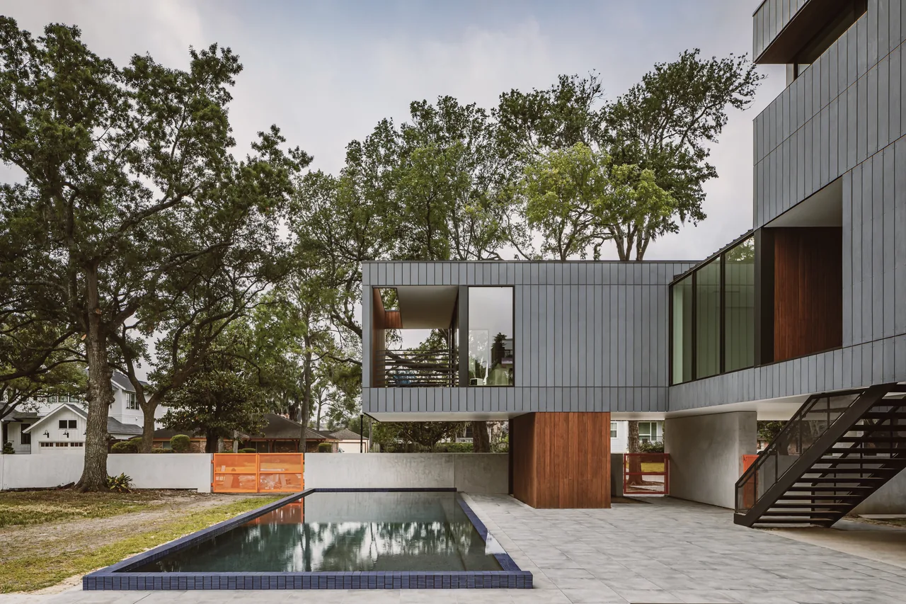 Modern residence with vertical ribbed siding, wood accents, black window frames, and a pool in the foreground.