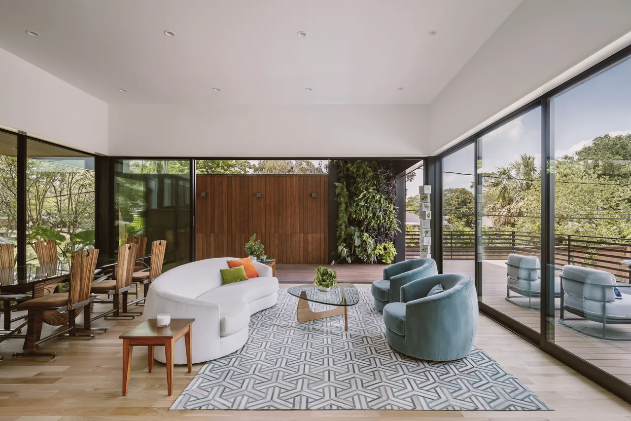 Interior living area of Grennoch Residence with floor-to-ceiling glass walls overlooking an outdoor deck and garden wall.