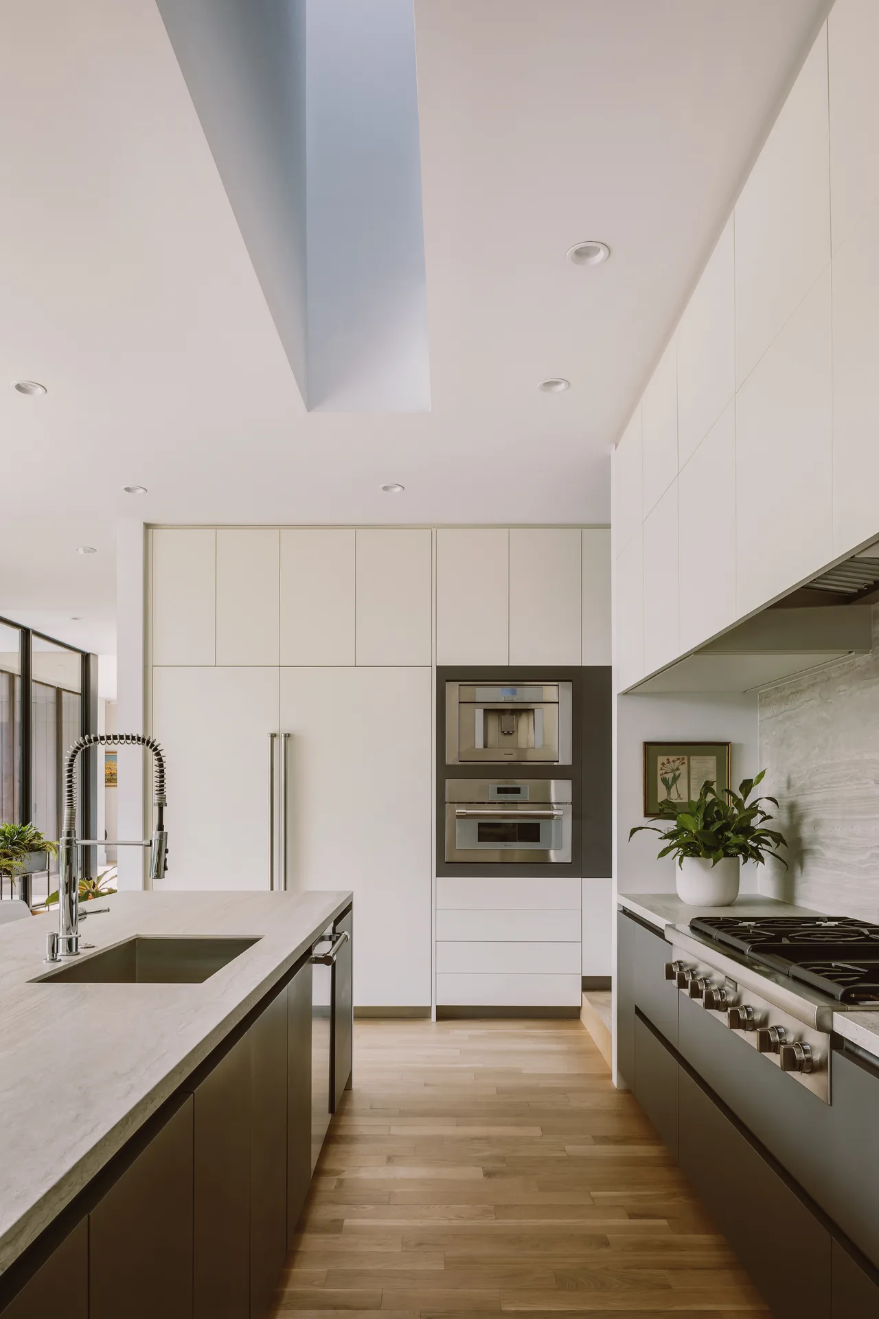 The Grennoch Residence kitchen features white upper cabinets, gray lower cabinets, and built-in stainless steel appliances.