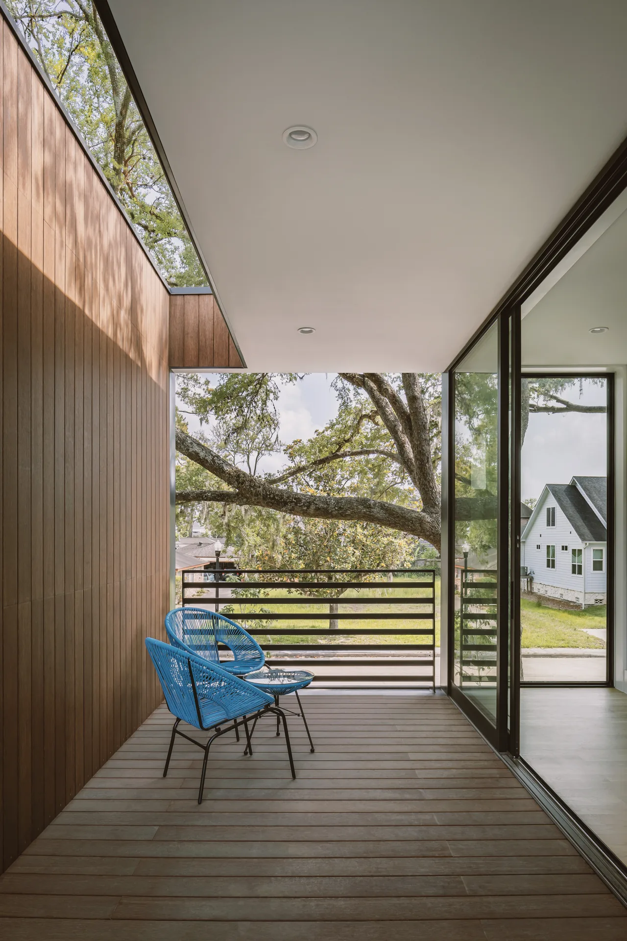 The Grennoch Residence features a covered patio with wood siding and large sliding glass doors.