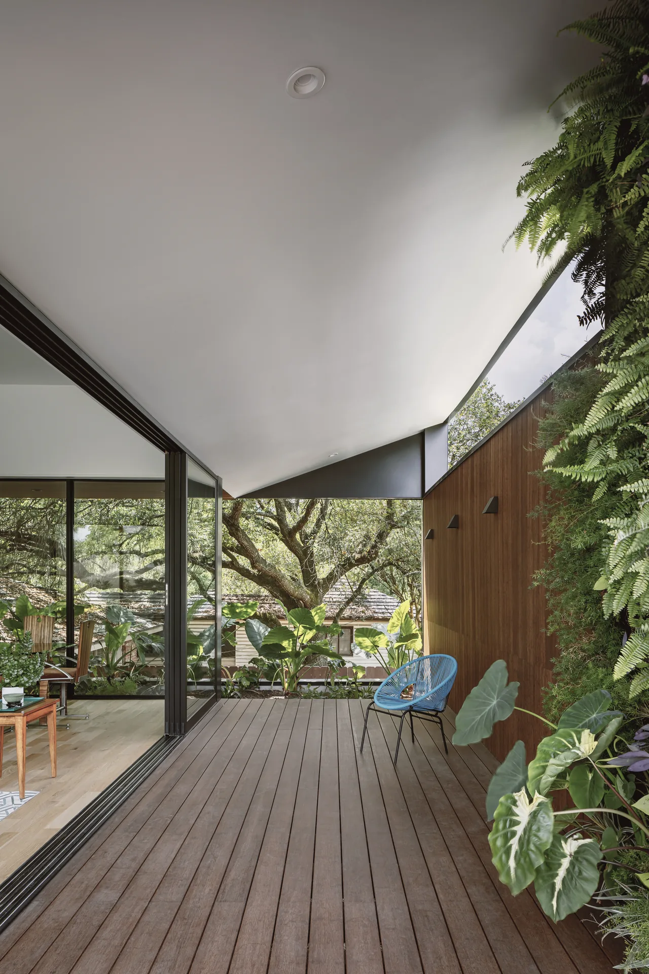 The Grennoch Residence features a covered patio deck with wood flooring and a vertical garden wall.