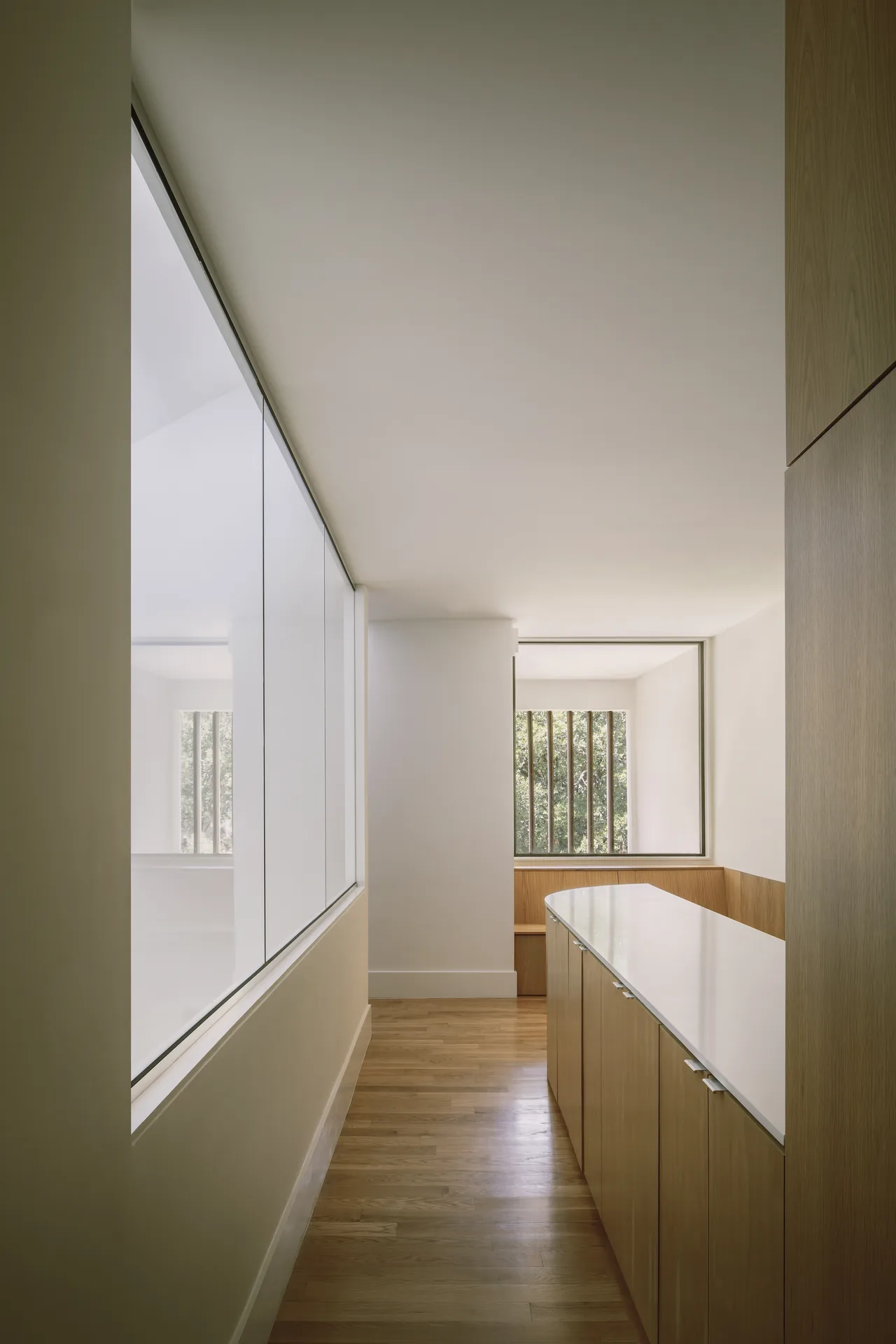 Hallway area with wood cabinetry and a large window featuring vertical bars shows minimalist design.