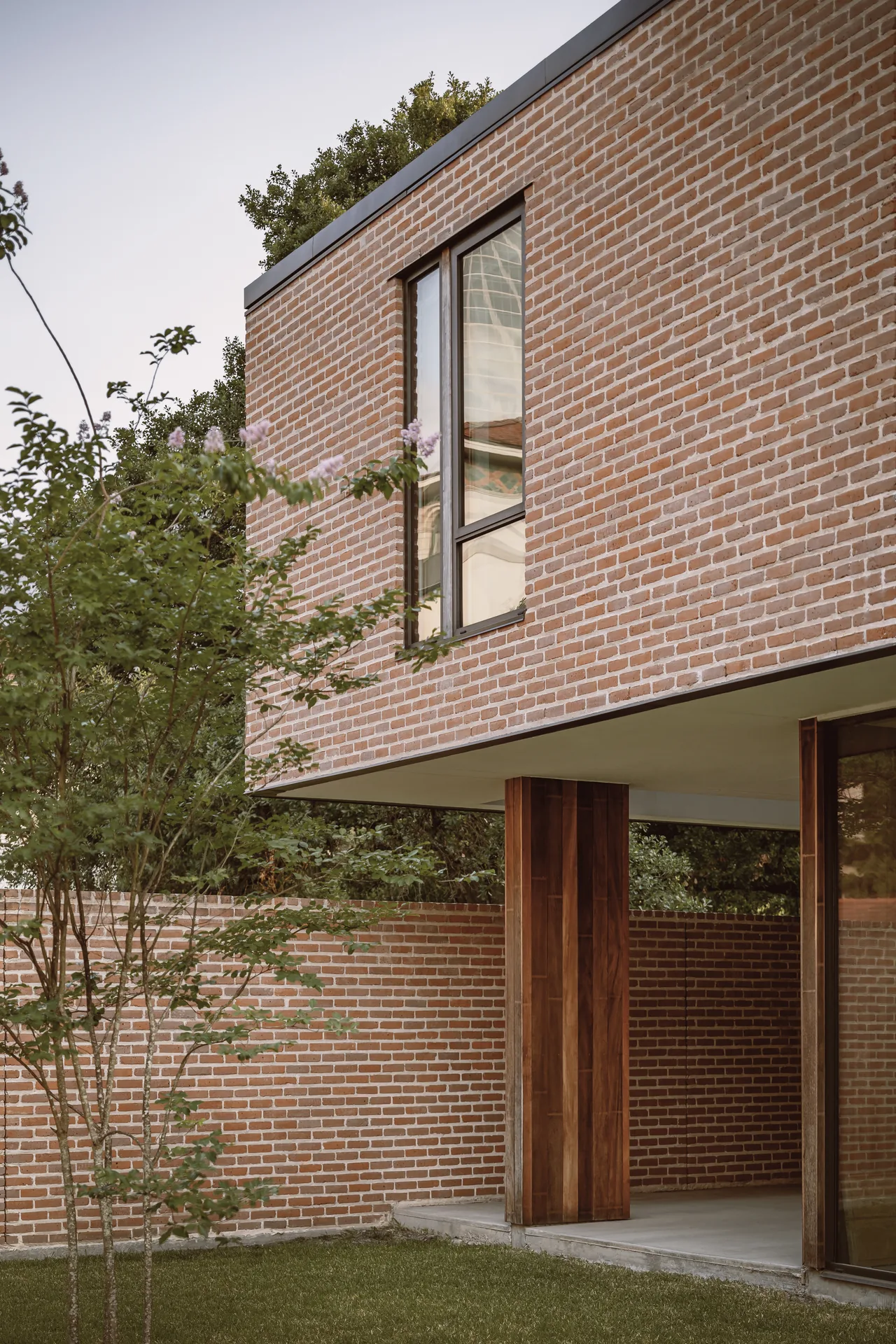 Exterior corner of Rice Magister House with wood-paneled columns and vertical window bars on brick wall.