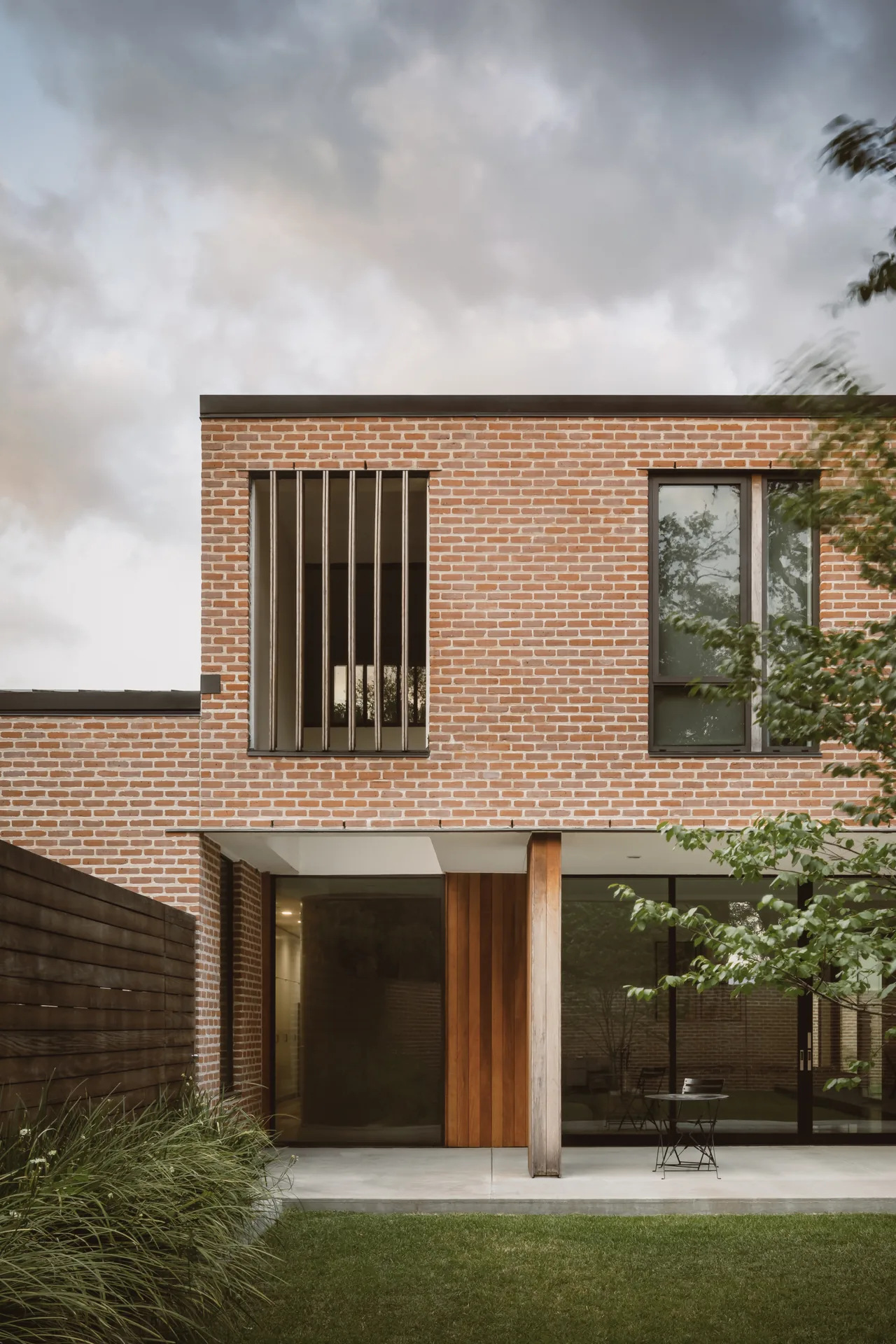 The Rice Magister House features a brick facade combined with vertical wood paneling and large windows.