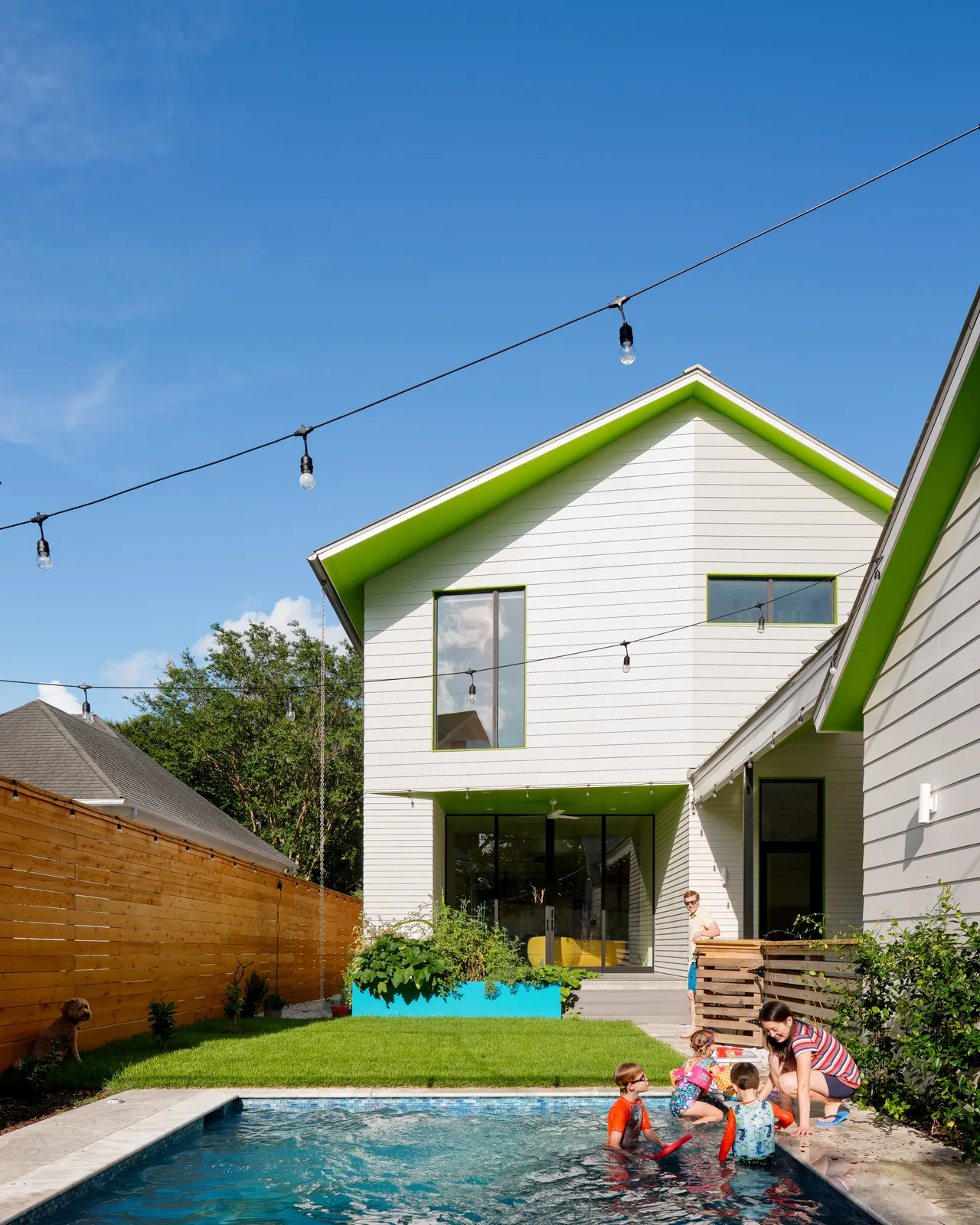 Allston Residence showing exterior rear with green trim and a small pool under string lights.