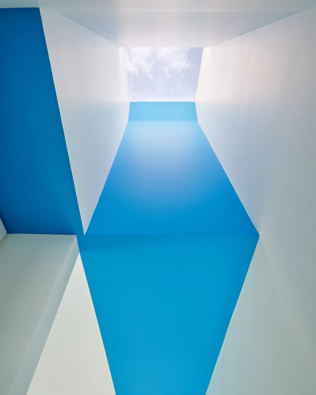 Vertical skylight in a white and blue painted architectural structure allowing daylight inside.