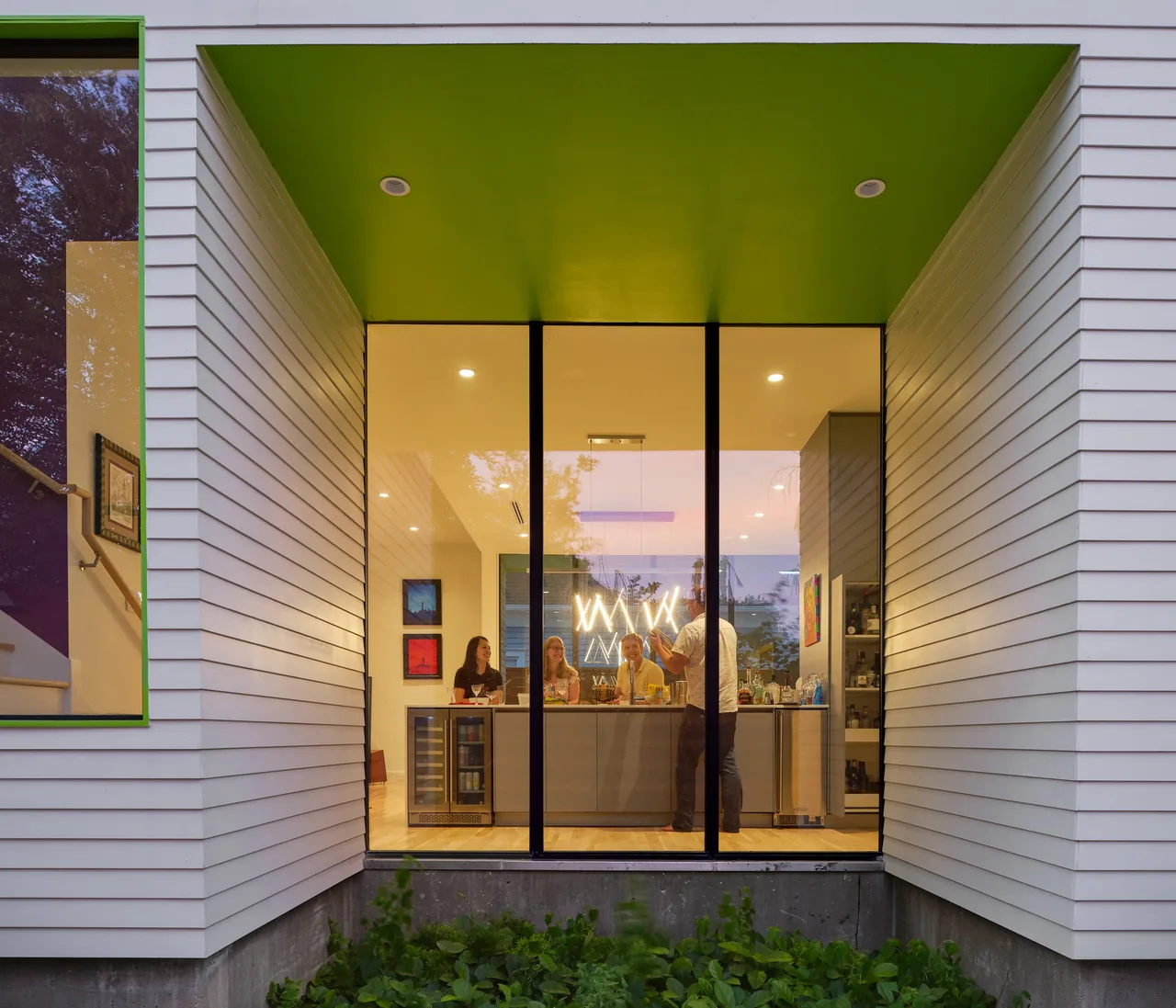 Exterior view of the Allston Residence kitchen with large floor-to-ceiling windows and distinctive green ceiling overhang above the window.