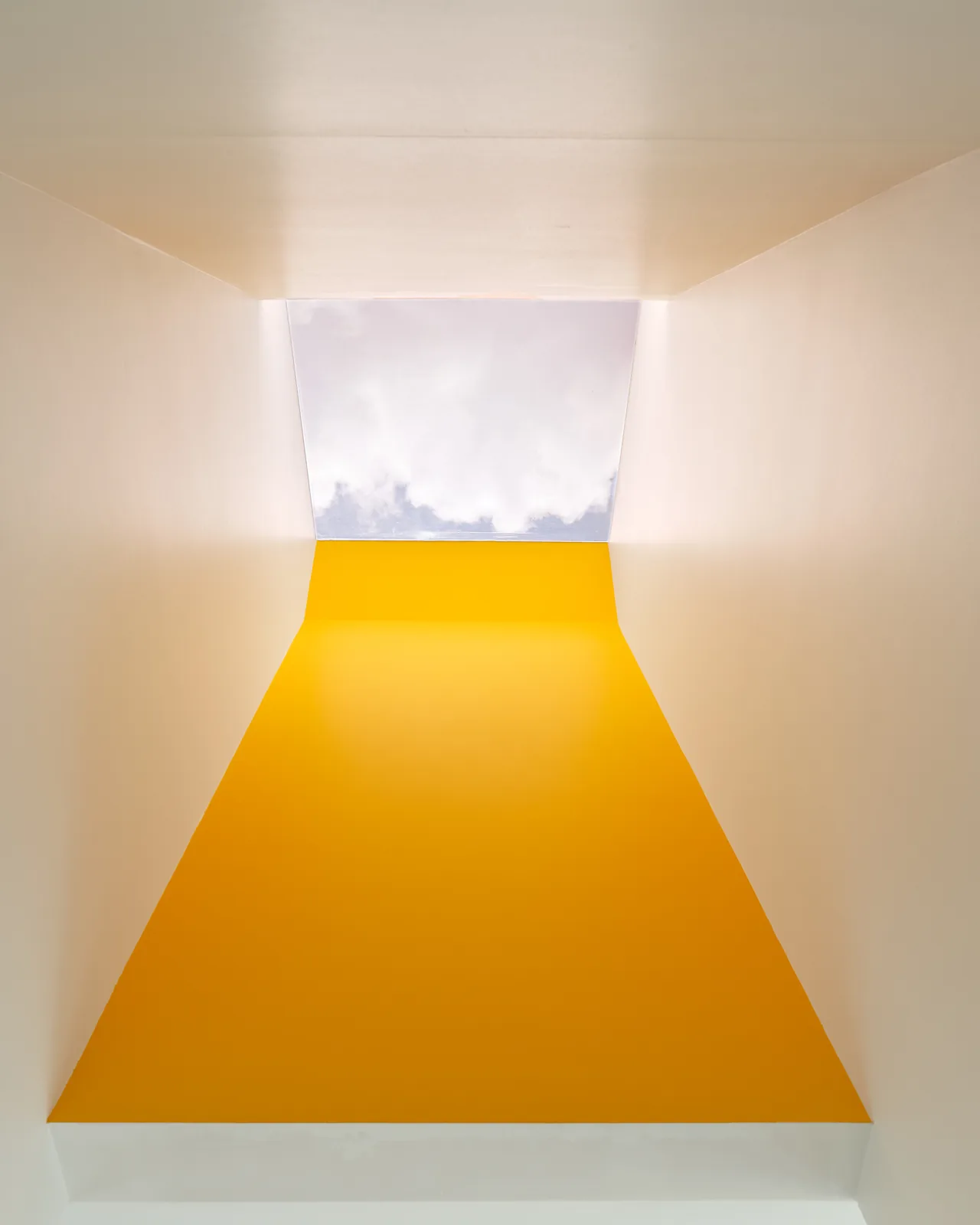 Interior view of a vertical skylight with an angular yellow accent wall and white walls at the Allston Residence.