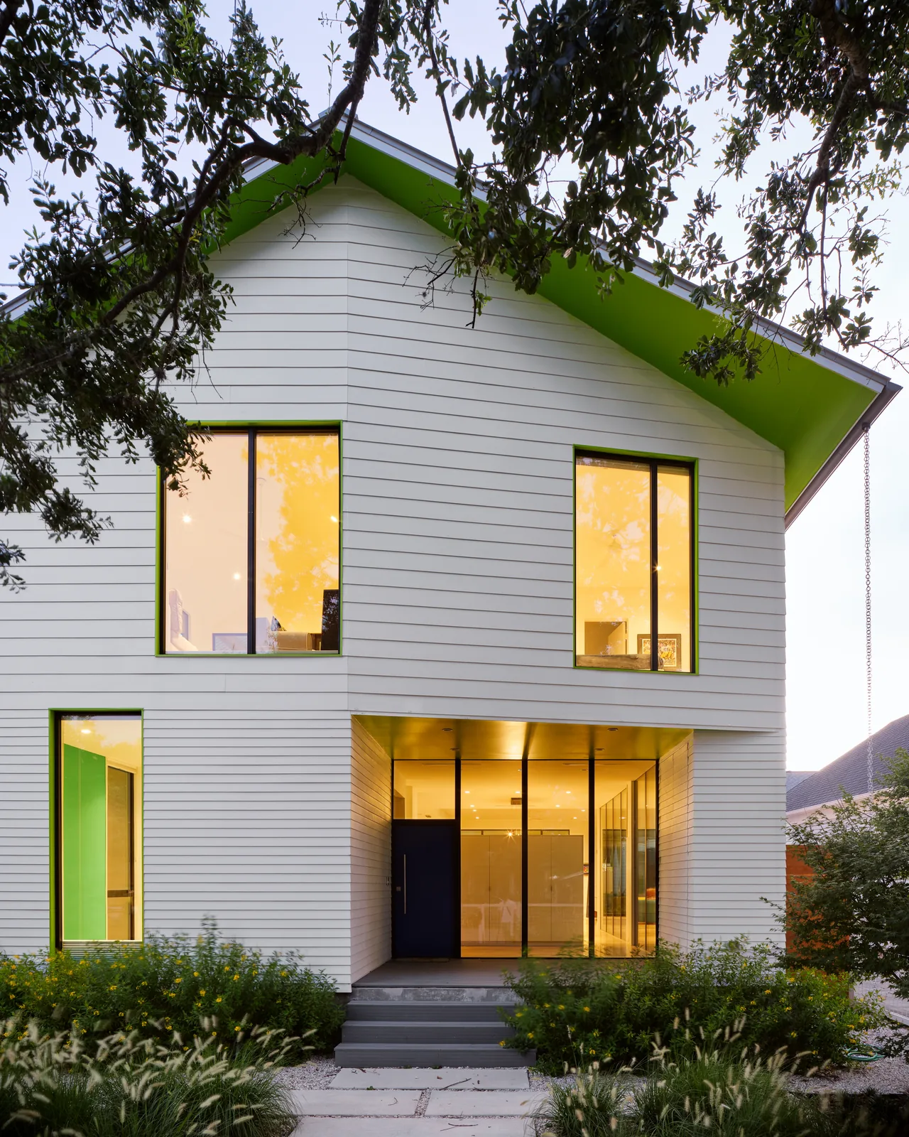 The Allston Residence features a white siding exterior with large windows and a striking green overhang under a gable roof.