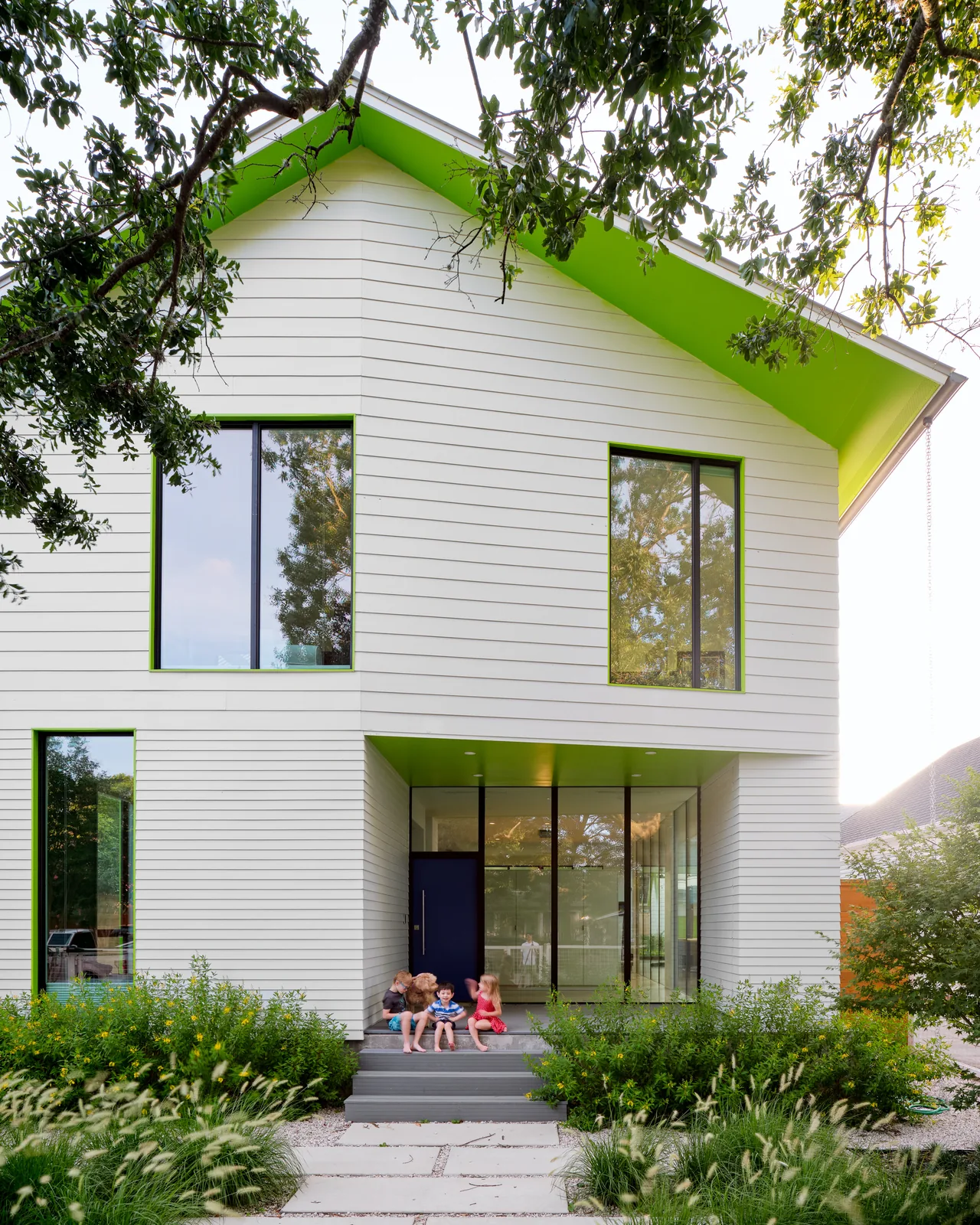 The Allston Residence features white horizontal siding with green accents and large rectangular windows.