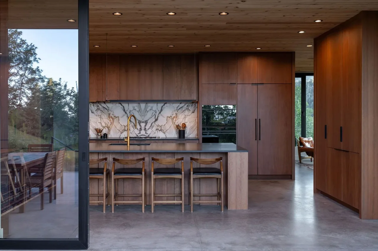 Kitchen interior featuring wood paneling, marble backsplash, and floor-to-ceiling glazing on the corner.