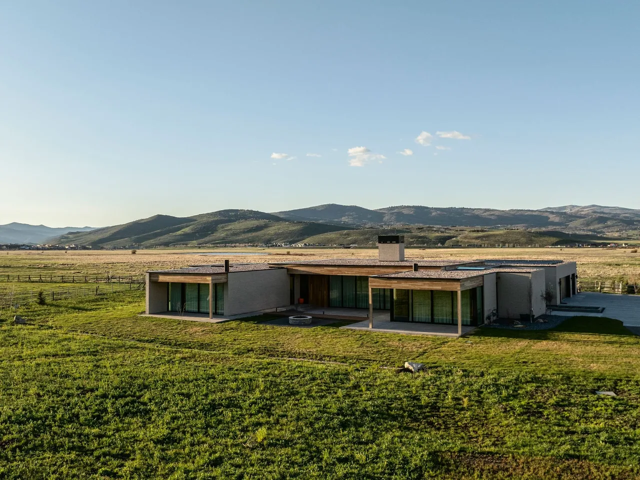Modern single-story house featuring wood and stucco exterior with floor-to-ceiling windows and covered patios.