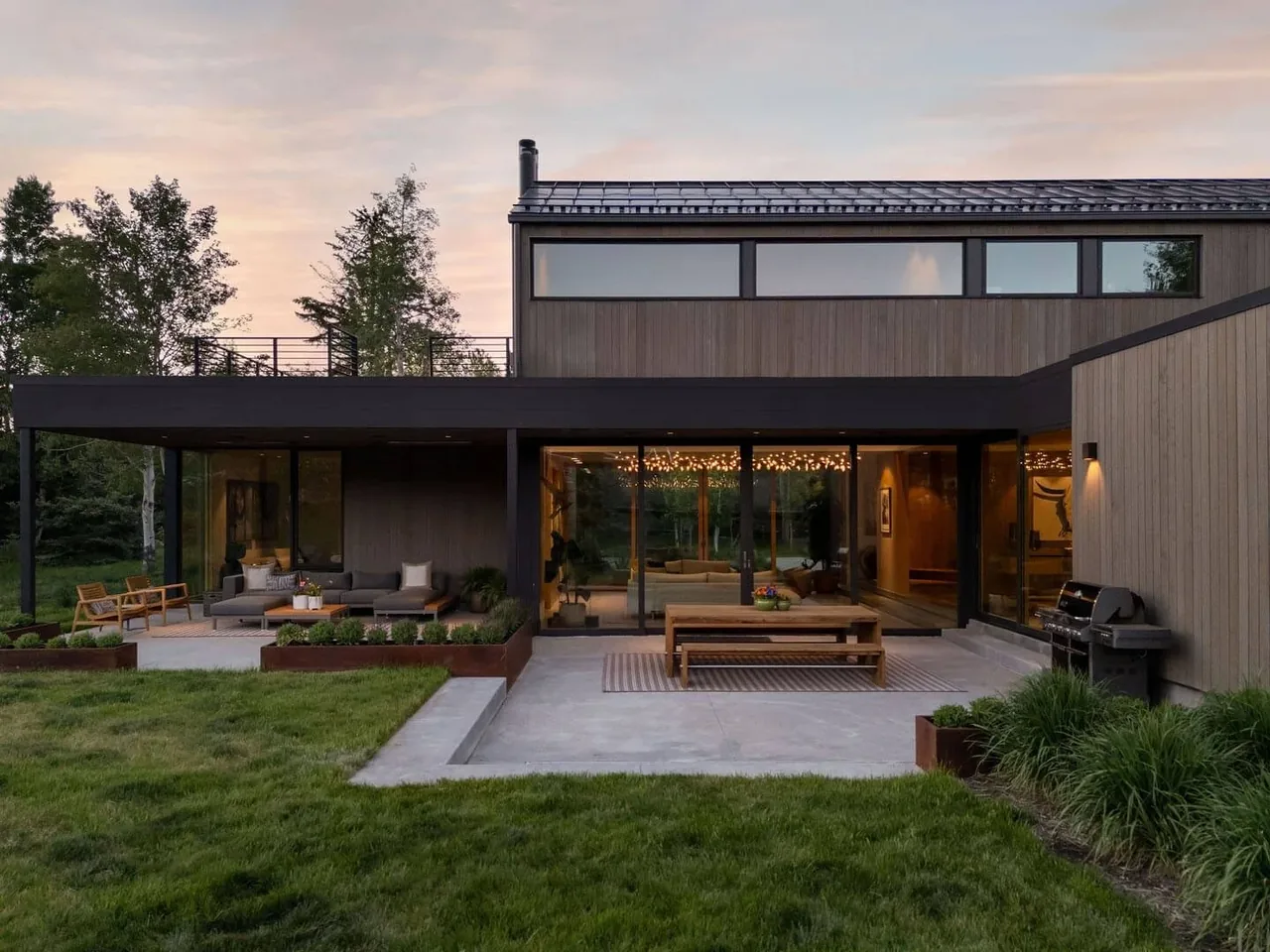 The equestrian project features vertical wood siding, black window frames, and integrated outdoor living spaces.