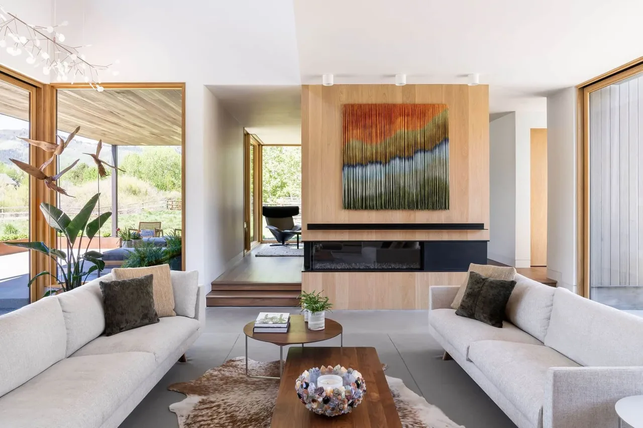 Living room features light wood paneling, black linear fireplace, and large windows with natural views.