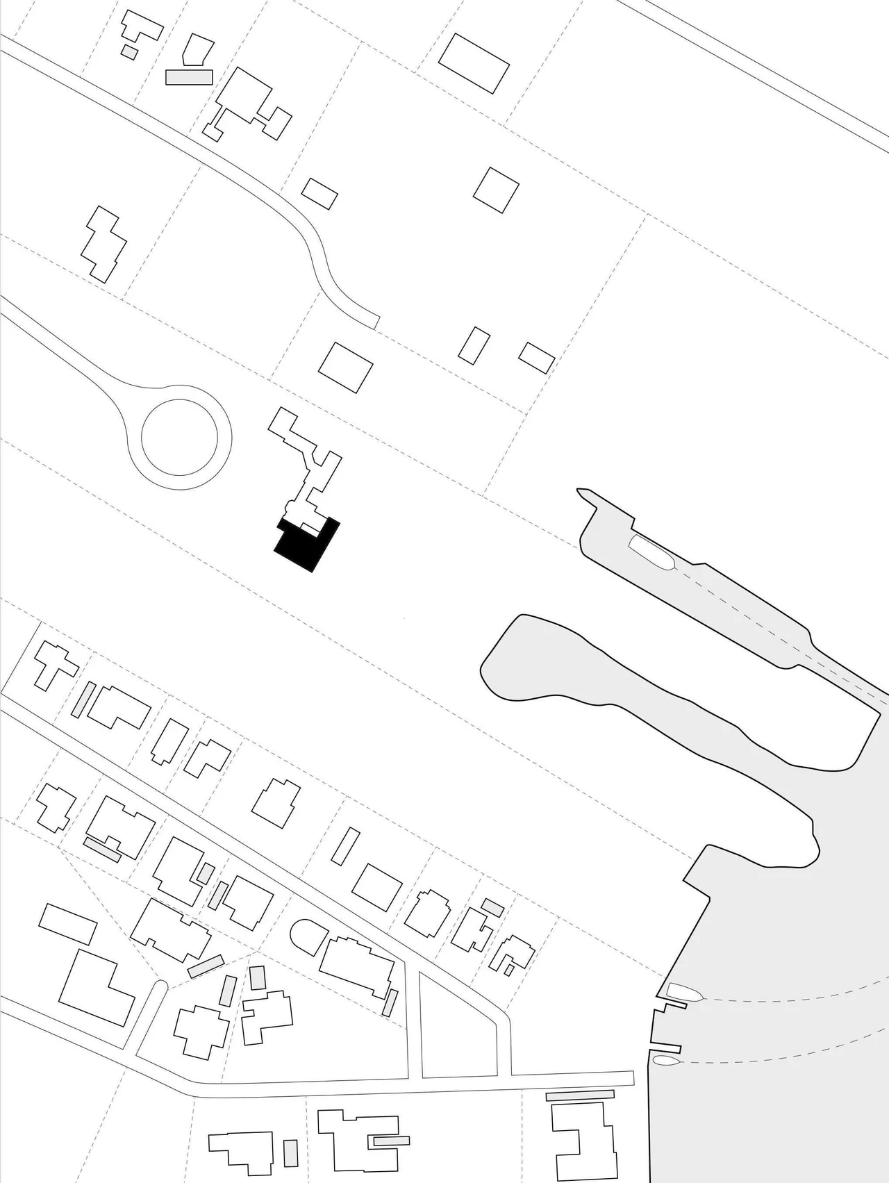 Black-highlighted building footprint within a site plan near other buildings and a water body.