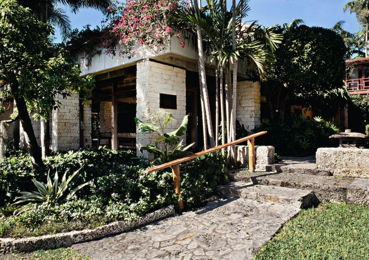Stone building with open sides and tropical landscaping at The Kampong project.