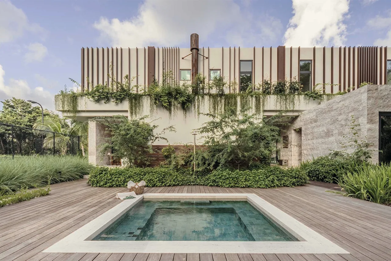 Angel Oaks features a modern two-story home with a rectangular pool surrounded by wood decking and abundant greenery.